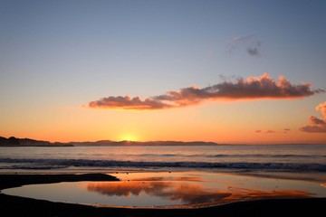 日の出の太陽と水溜りに映る朝焼けに染まる雲
朝焼けの茜色の空が海岸の水溜りに映って美しかった。