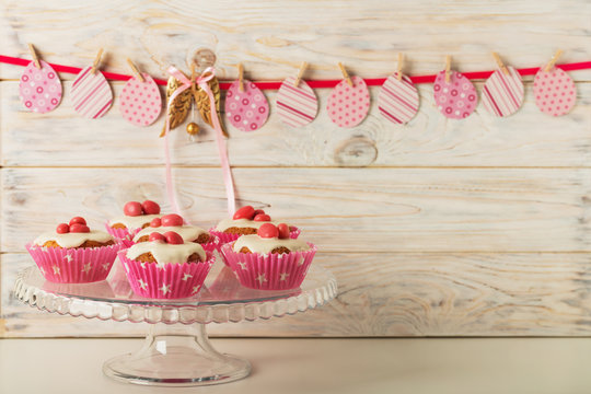 Easter cupcakes with white icing decorated with pink candy and ribbons.