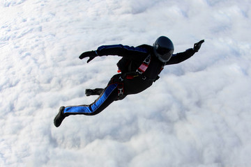 Naklejka na ściany i meble Alone skydiver is above the white clouds.