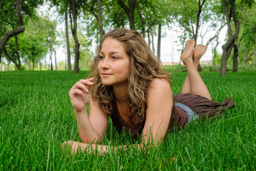 Naklejka na ściany i meble Young beautiful smiling woman relaxes on grass