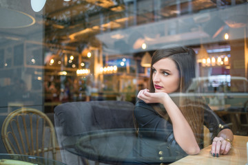 Beautiful young girl in blue glasses posing in cafe
