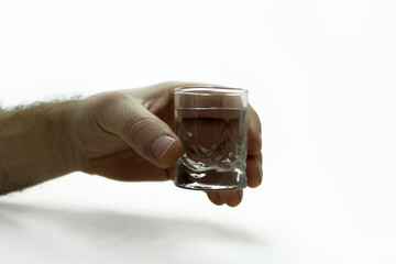 Man's hand holding a glass of vodka.