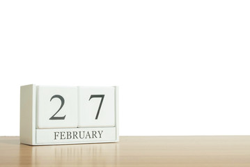Closeup surface white wooden calendar with black 27 february word on blurred brown wood desk isolated on white background with copy space , selective focus at the calendar