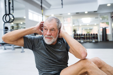 Fit senior man in gym working his abs, doing crunches.