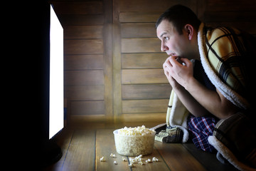Naklejka premium young man watching television at home on the floor