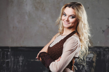 Fototapeta premium Portrait of a beautiful steampunk woman in a pant suit with vest, over grunge background.