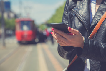 Using cellphone with de-focused city tram.