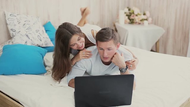 Happy young couple looking at laptop at home