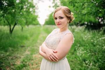 Young overweight girl at beige dress posed background spring garden.