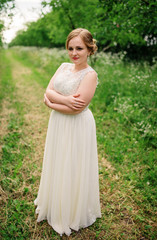 Naklejka premium Young overweight girl at beige dress posed background spring garden.