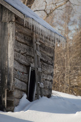 Snowy old log cabin barn with icicles