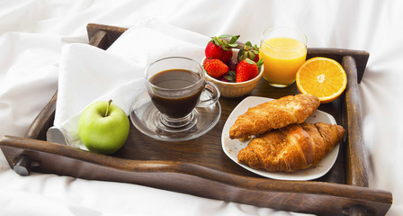 Naklejka na ściany i meble Bed breakfast with croissants,fruits, coffee and juice