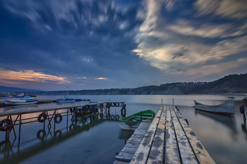 exciting long exposure seascape on harbor with wooden pier and boat
