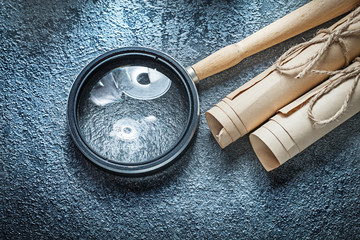 Vintage paper scrolls magnifying glass on black background