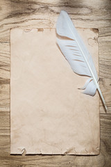 Vintage sheet of paper feather on wooden board