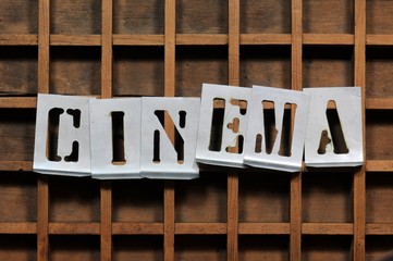 Word CINEMA with stencils on old typefaces wooden container.