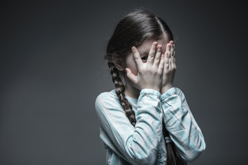 Little frightened girl peeping through fingers