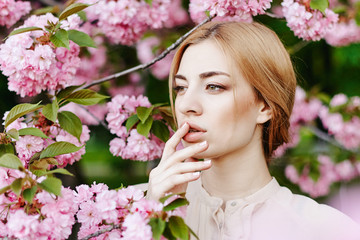 Obraz premium Spring portraits gorgeous young woman on cherry blossom background