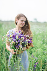 Naklejka na ściany i meble beautiful young woman with a bouquet of flowers on the summer meadow