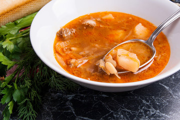 Close up view of plate and spoon with red beetroot soup or borsch on dark marble background. .