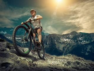 Man in helmet and glasses stay on the bicycle under sky with clo