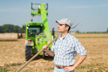 Portrait of a smiling farmer holding a pitchfork