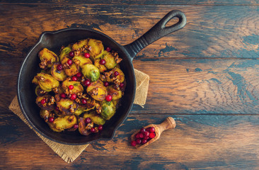 Roasted Brussels sprouts with caramelized walnuts and cranberries in a cast iron frying pan on a...