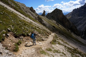 Naklejka premium Wanderin alleine unterwegs mit Rucksack und Stecken in den Bergen in felsiger Gebirgslandschaft