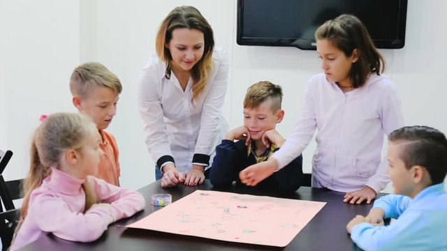 Children making move on pre-marked surface of board game at classroom