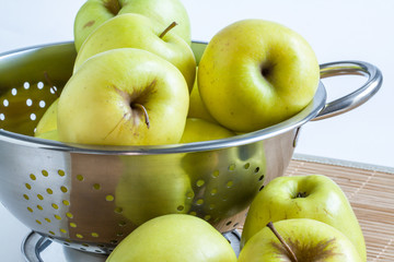 Pommes Golden dans une écumoire sur fond blanc