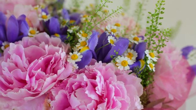 Rotating bouquet of flowers. Peonies, irises, chamomiles (close-up)