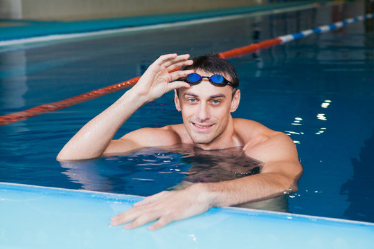 Portrait of a fit swimmer with goggles in pool at fitness center