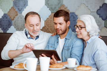 Positive man and their grandparents resting in the cafe