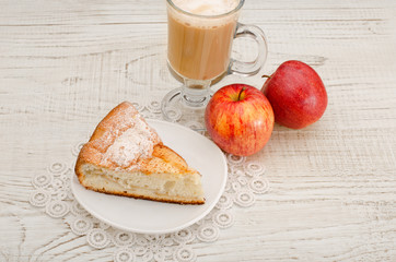 Piece of apple pie, cappuccino and ripe apples on a light wooden background, top view