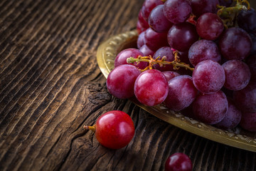 Fresh red grapes in old bowl on wooden table