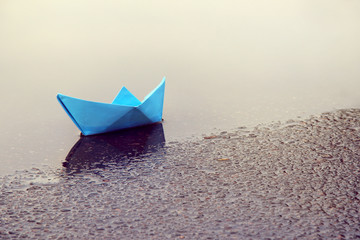 waiting for favorable wind/ children's paper boat in a puddle of spring