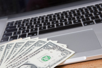 US dollars and a modern laptop. Business and online shopping concept image. 