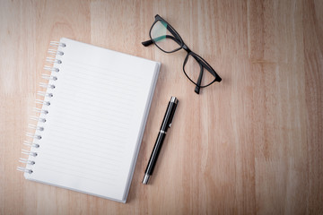 blank notebook with pen on wooden table, business concept.