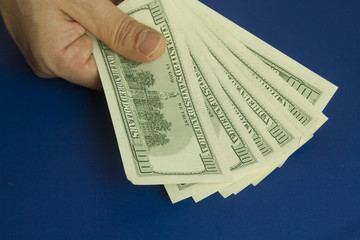 Man's hands holding dollars on dark blue background