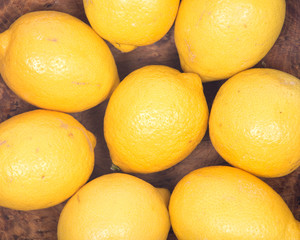 Ripe organic lemons in wooden bowl like background