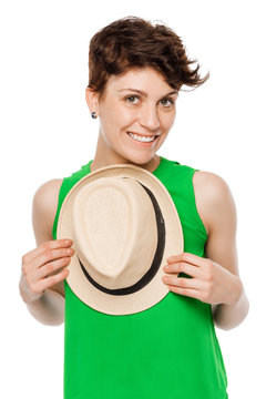 cute brunette in a green top, holding a hat on a white background isolated