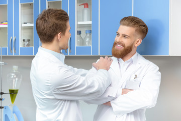 Fototapeta premium portrait of smiling scientists discussing work in lab during break