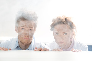 portrait of scientists looking out behind table after experiment in lab on white