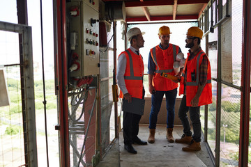 Group of workmen standing in industrial elevator discussing construction site progress