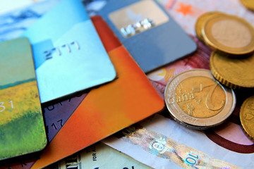 stack of multicolored credit cards and euro coins  scattered around, close-up.