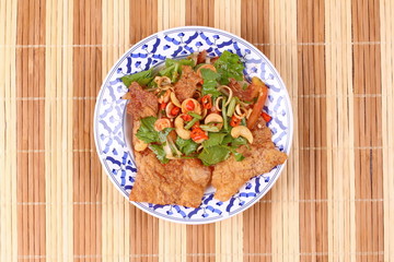 Spicy and sour mixed herb salad with crispy pork served .