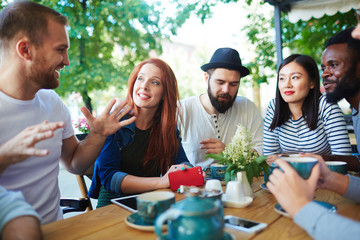 Group of contemporary young people having conversation at hangout