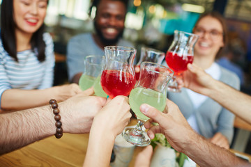 Hands of friends with glasses of drinks during toast