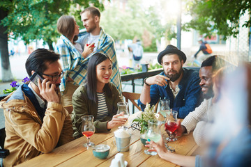 Contemporary youth with drinks spending time in outdoor cafe