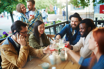 Youthful friends toasting with drinks during hangout
